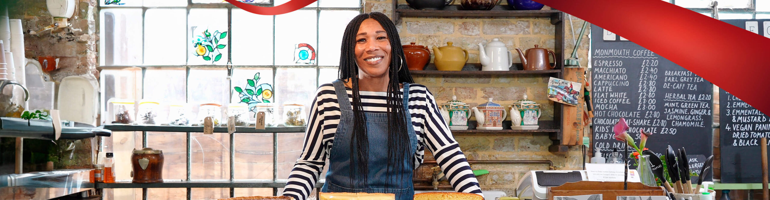 An underrepresented business owner behind the counter of her coffee shop.